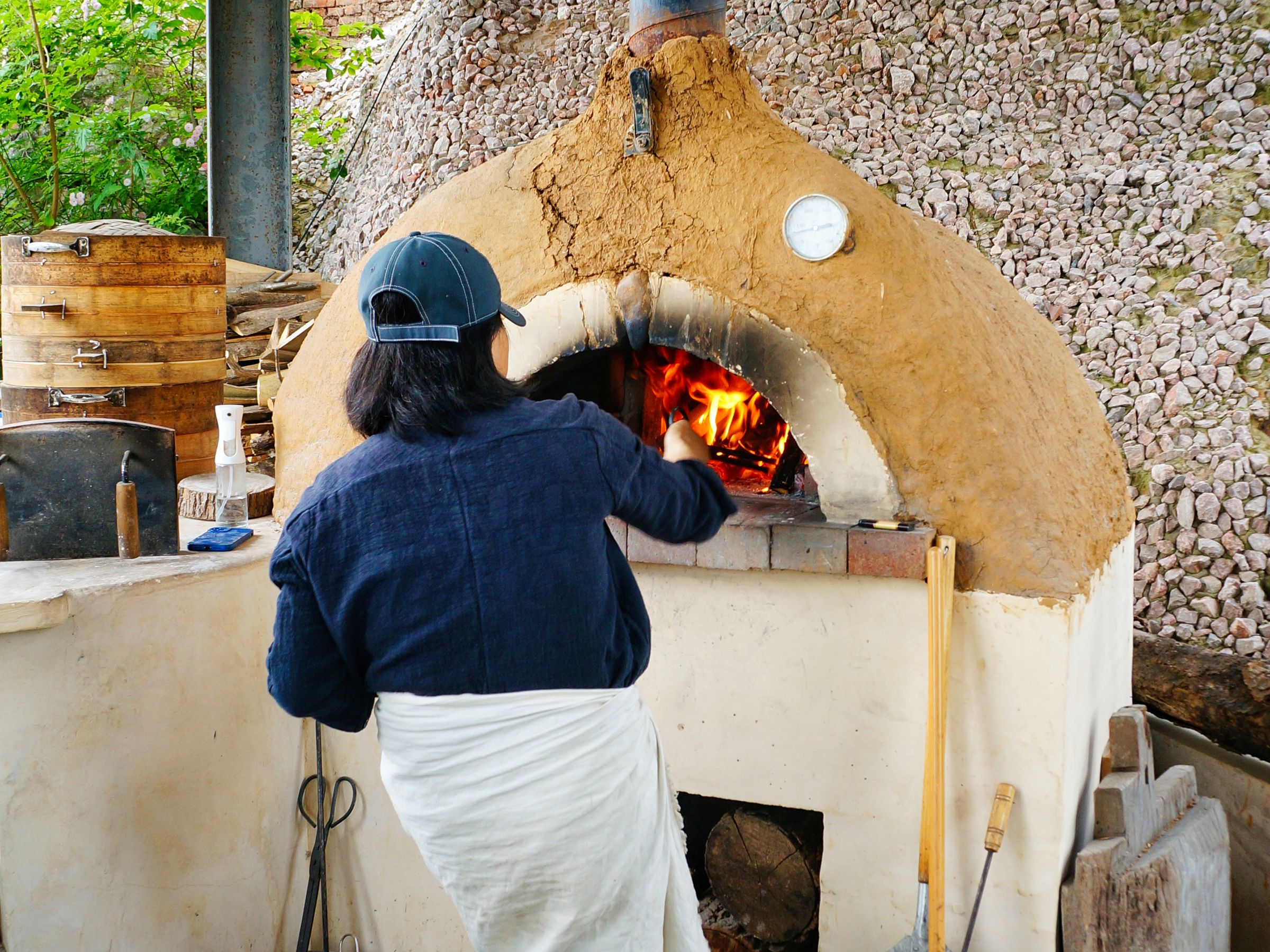 A baker sliding a loaf of bread into a wood-fired oven