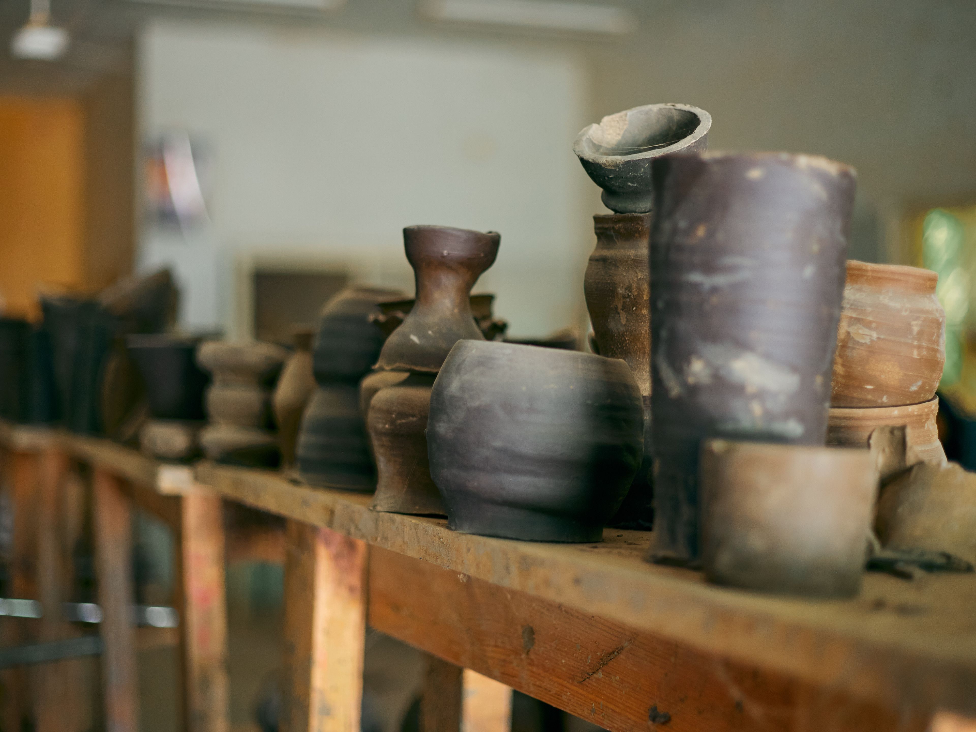 A shelf of handmade glazed pottery lined up in the studio